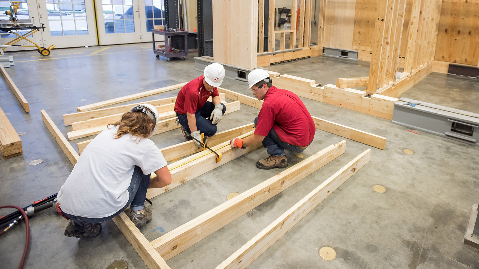 Three students work on building a structure.