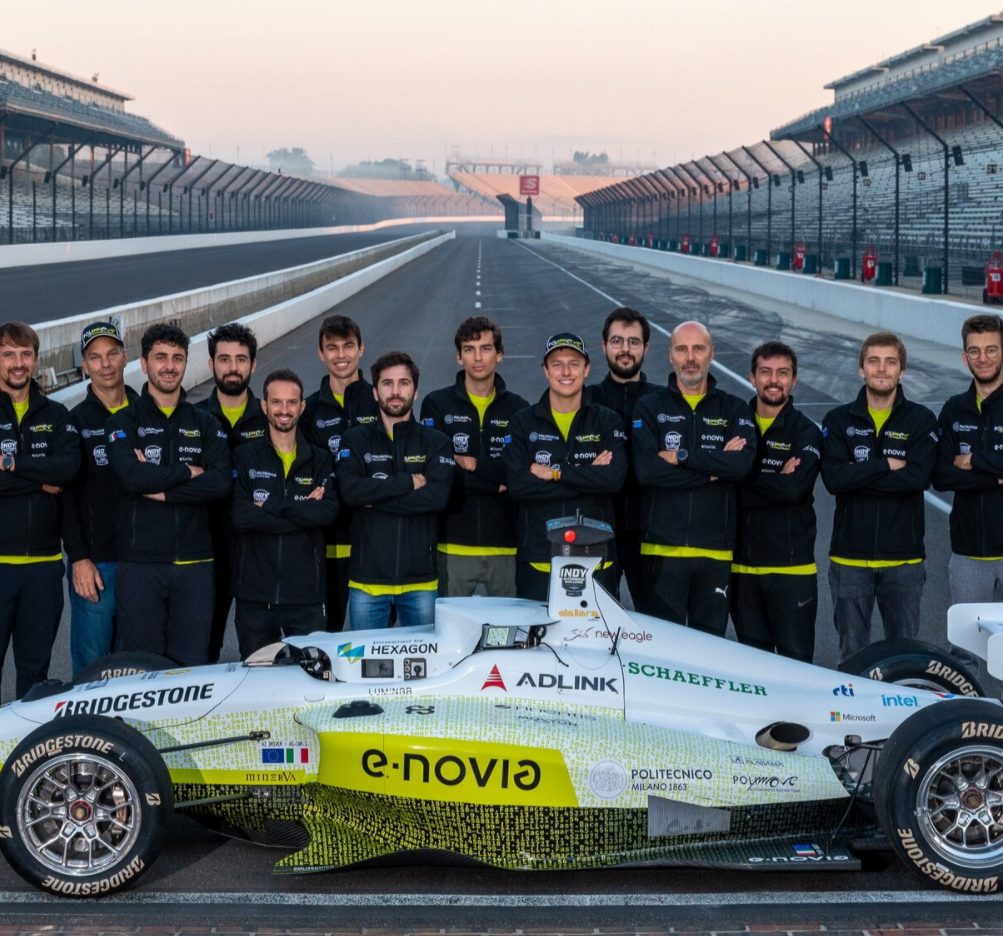 LinkedIn photo of a race car on a track with full team standing behind it